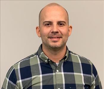 SERVPRO employee plaid shirt in front of beige wall