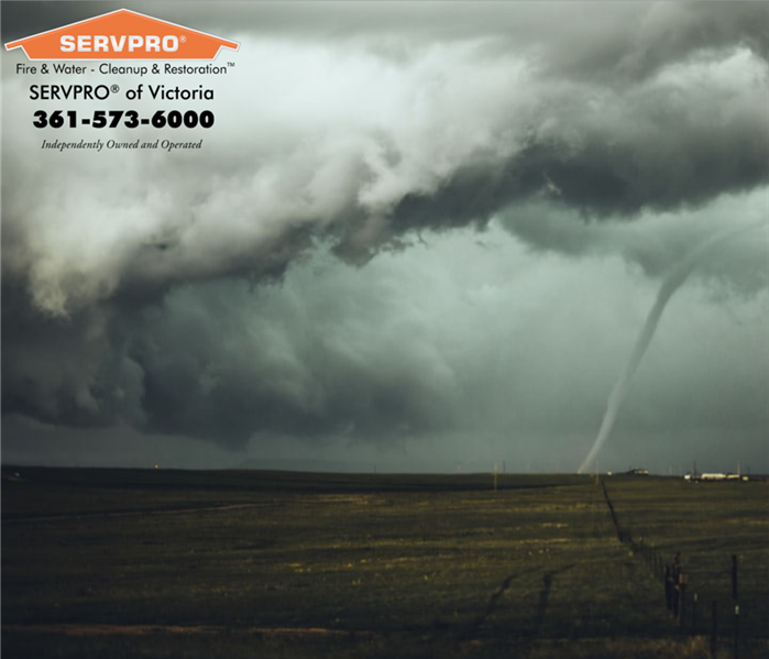 Cloudy skies.  Tornado in the background near the right side of photo.  SERVPRO of Victoria information at the top left.